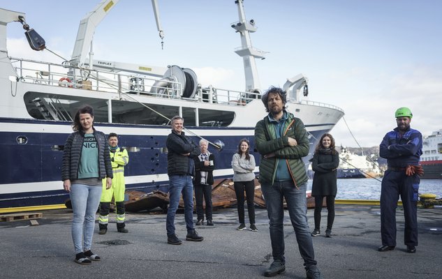 foto av en gjeng forskningspersonell som står foran en båt